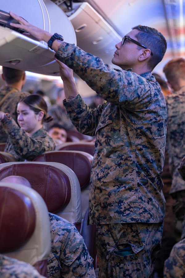 U.S. Navy Petty Officer 1st Class Daniel Formano, a hospital corpsman with Combat Logistics Battalion 5 (Reinforced), Marine Rotational Force – Darwin 24.3, reaches for his luggage from the overhead bin of a Boeing 777 at Royal Australian Air Force Base Darwin, NT, Australia, March 24, 2024. MRF-D 24.3 is part of an annual six-month rotational deployment to enhance interoperability with the Australian Defence Force and Allies and partners and provide a forward-postured crisis response force in the Indo-Pacific. Formano is a native of California. (U.S. Marine Corps photo by Sgt. Cristian L. Bestul)