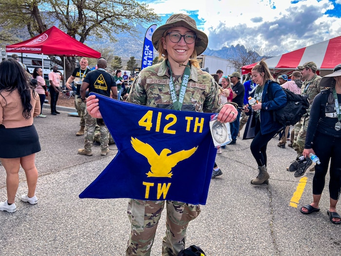 Staff Sgt. Wendy Updegrave, Flight and Operational Medicine Clinic noncommissioned officer-in-charge, 412th Operational Medical Readiness Squadron, shows off the 412th Test Wing guidon and a photo of her grandfather, which she carried with her during the Bataan Memorial Death March at White Sands Missile Range, New Mexico, March. 16. (Photo courtesy of Staff Sgt. Wendy Updegrave)