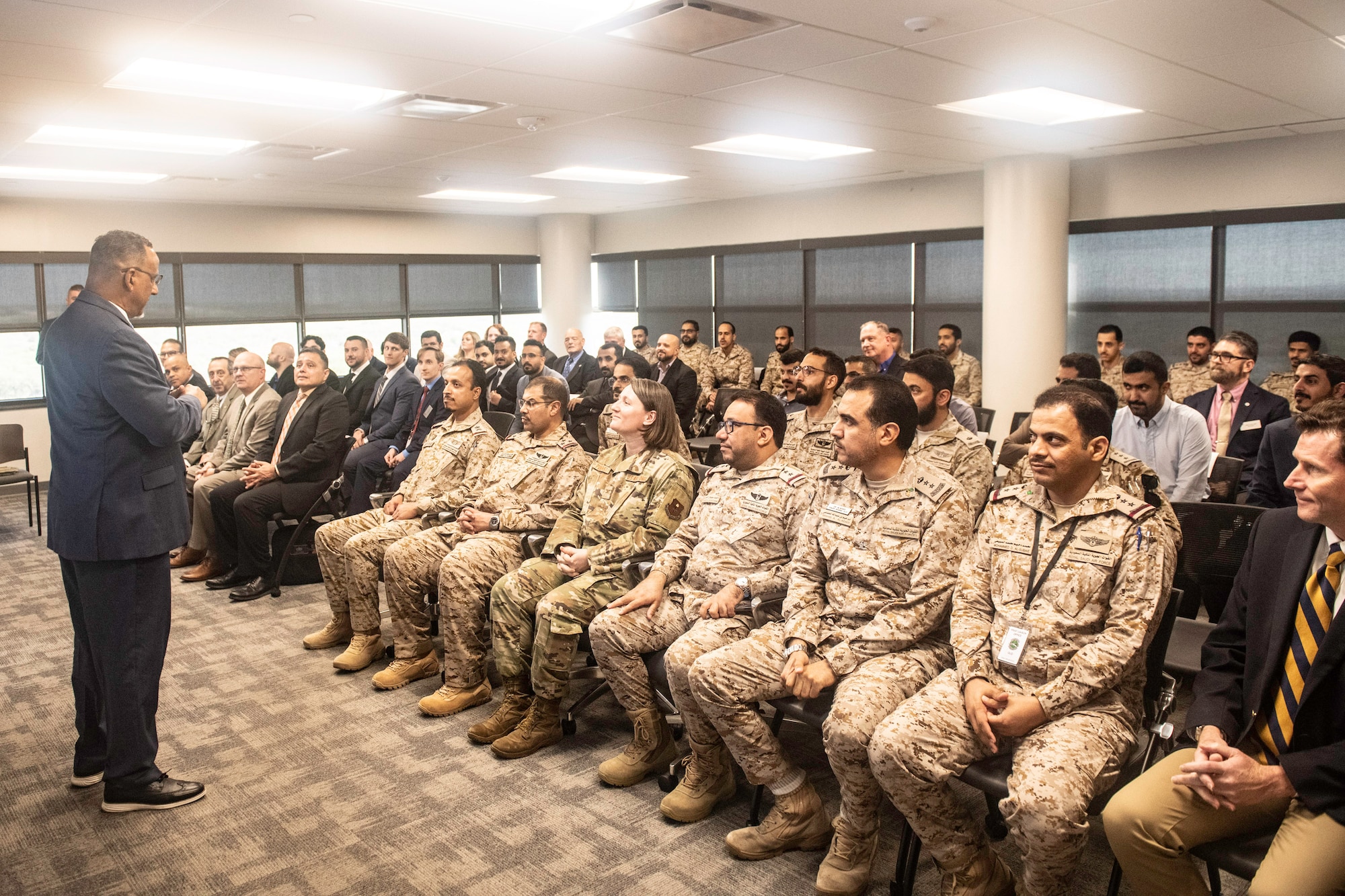 male speaker standing in front of a room full of military officers and civilians
