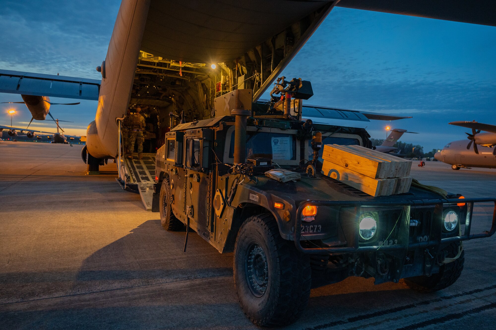 Airmen load a truck into the back of a C-130J at night