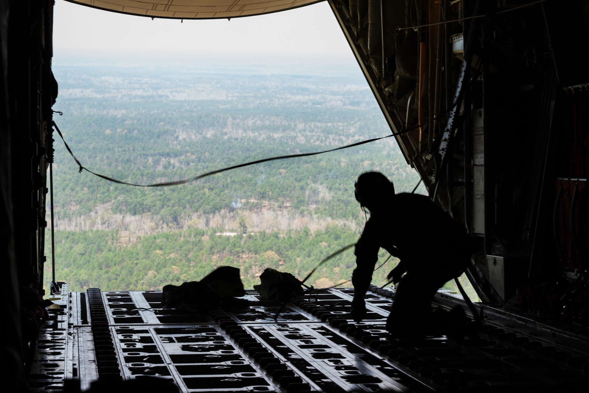 An airman drops a load out the back of a C-130J