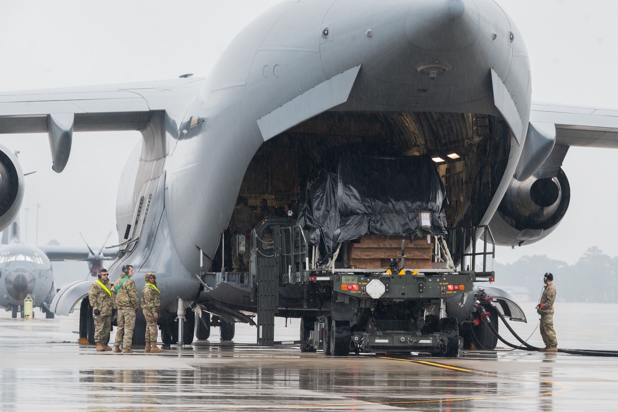 airmen load equipment into the back of a C-17