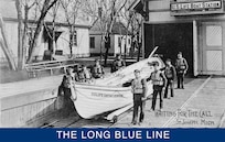 A photograph of the U.S. Life Saving Service crew posing with its surfboat in front of U.S. Life-Saving Station at St. Joseph, Michigan, from the Digital Collections of the Detroit Public Library.