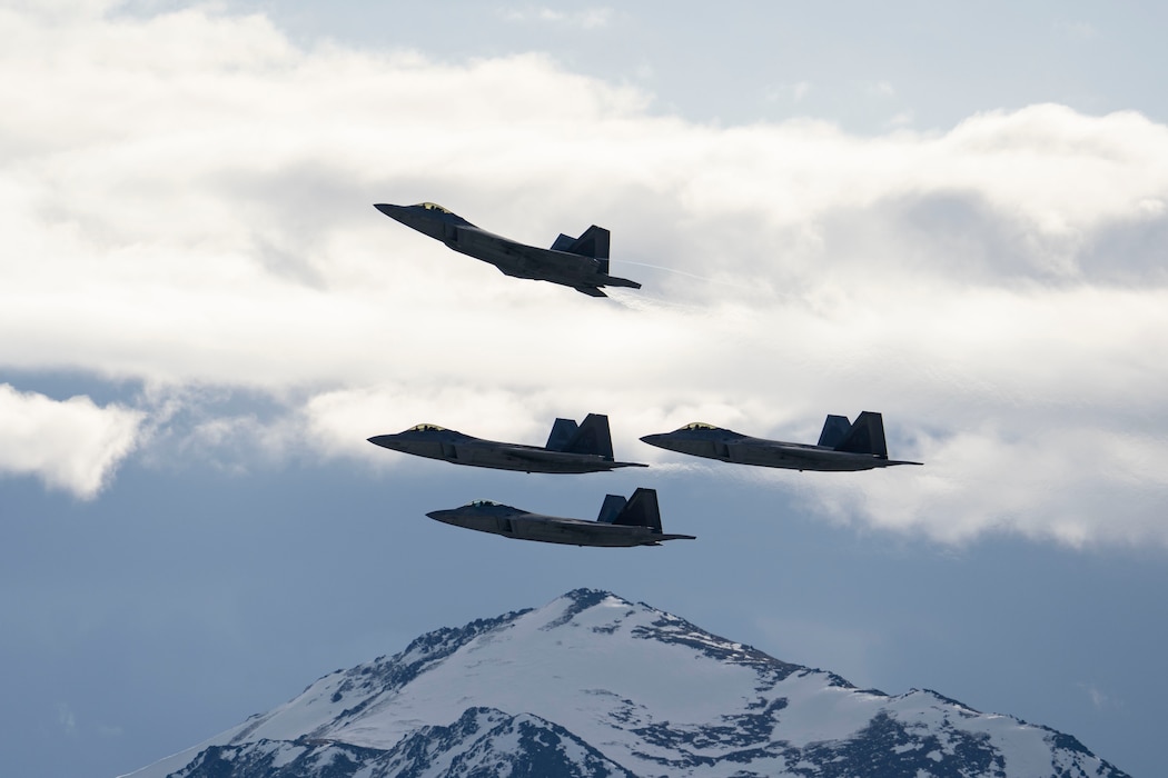 Four F-22 Raptors conduct a missing man formation flyover
