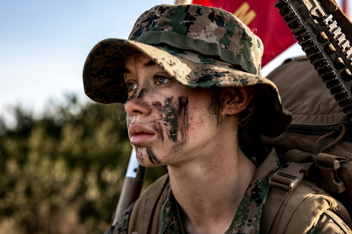 Close-up of a uniformed Marine’s face, partially covered in face paint.