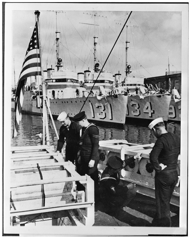 British and American sailors examine depth charges in front of three US Navy destroyers prior to their transfer to the Royal Navy as part of the Destroyers for Bases deal in September 1940. (Courtesy Library of Congress)
