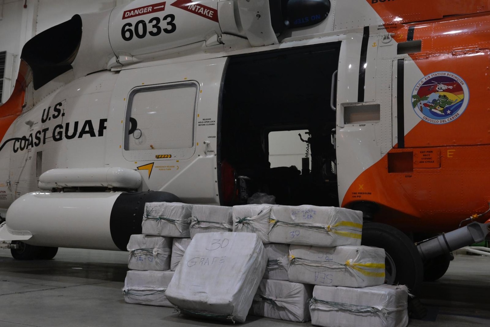 A U.S. Coast Guard Air Station Borinquen helicopter aircrew forward-deployed to Operation Bahamas Turks and Caicos assists with the transfer of approximately 391 kilos of cocaine worth an estimated value of $7.5 million, March 26, 2024, at the Mayaguana Airport in The Bahamas. The illicit drugs were apprehended following a joint agency interdiction of a drug smuggling event on March 25, 2024 (U.S. Coast Guard courtesy photo)
