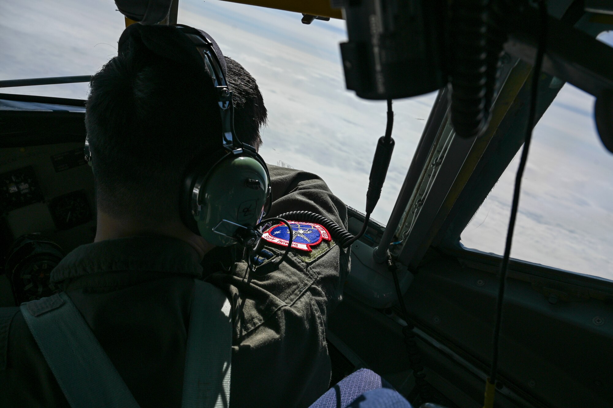 A pilot looks out the cockpit window of a jet.