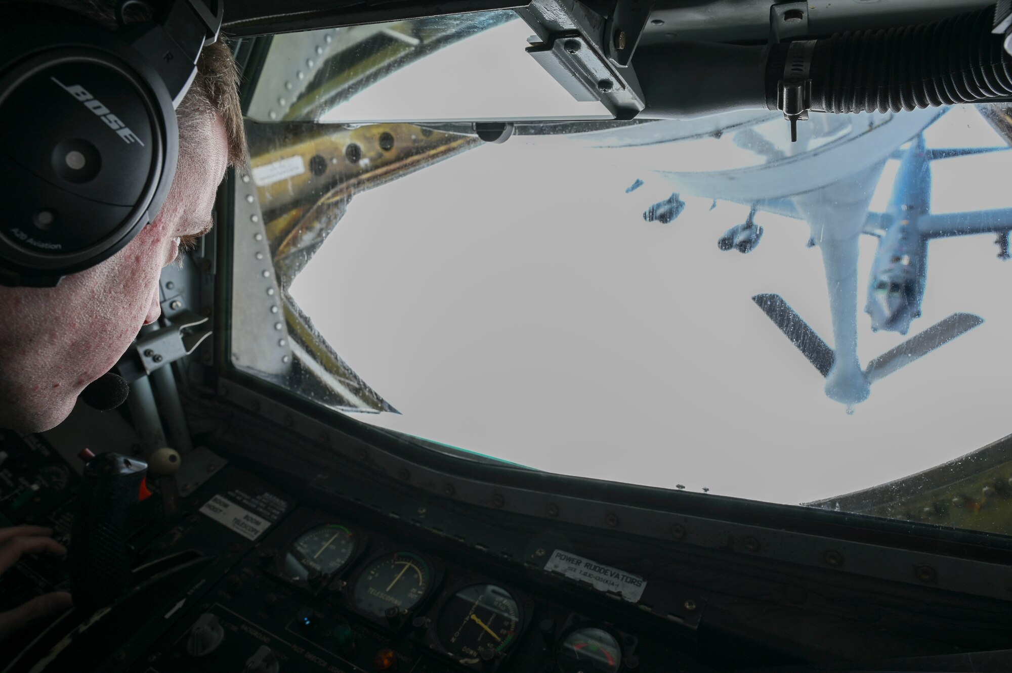 A boom operator directs a plane to the boom for refueling.