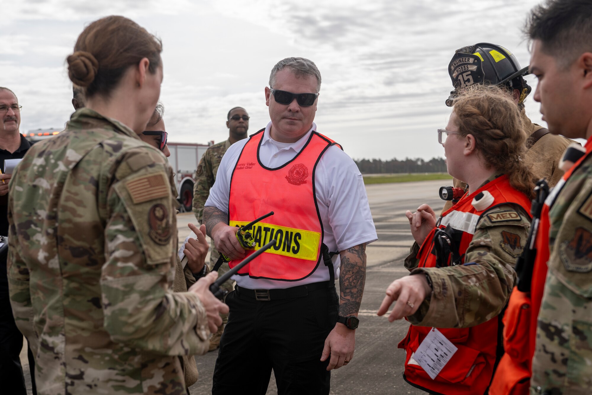 Jeremy Valler, 23rd Civil Engineer Squadron Fire Department operations officer, center, receives updates during an aircraft accident response exercise at Moody Air Force Base, Georgia, March 26, 2024. Aircraft accidents require response from first responders, the safety office, maintenance squadrons, and security forces. (U.S. Air Force photo by Senior Airman Deanna Muir)