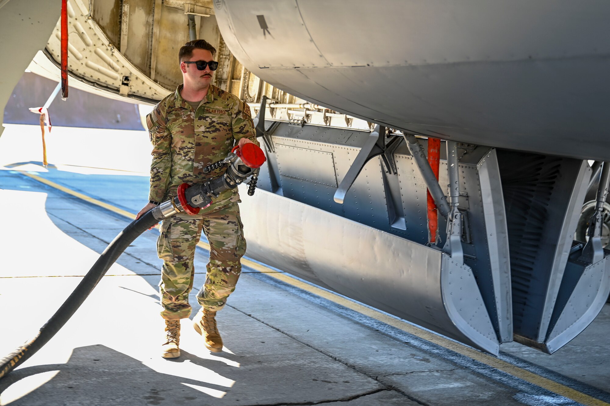 An Airman carries a fuels hose