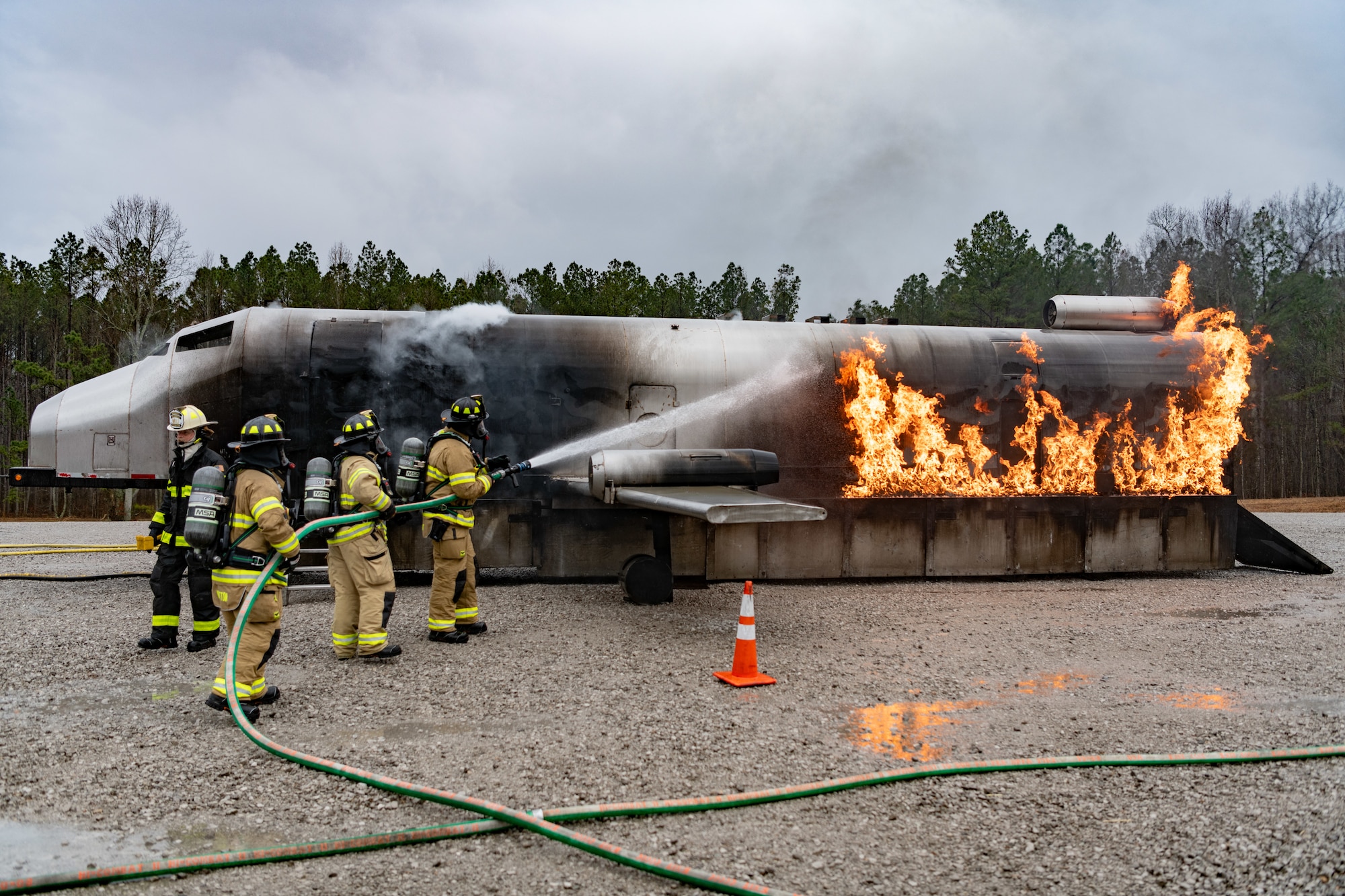 Firefighters with Arnold Air Force Base Fire and Emergency Services use a handline to combat a simulated aircraft fire during fuselage fire training March 5, 2024, at Arnold AFB, Tenn., headquarters of Arnold Engineering Development Complex. Arnold FES crews took part in live structural fire training Feb. 27-29, 2024, and live aircraft fire training March 5-7, 2024. (U.S. Air Force photo by Keith Thornburgh)