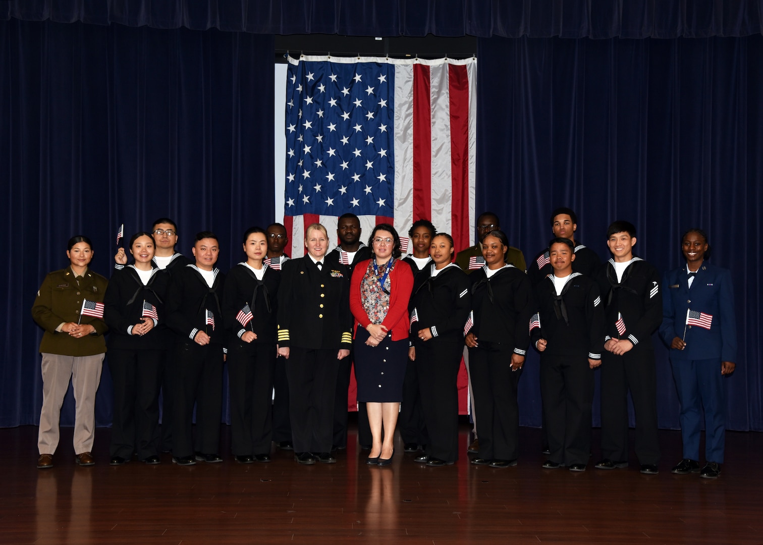 JOINT BASE SAN ANTONIO-FORT SAM HOUSTON – (March 27, 2024) – Capt. Jennifer Buechel, commanding officer, Naval Medical Research Unit (NAMRU) San Antonio, joined by Immigration Service Officer Yoli Fleming, with 15 service members from the U.S. Army, Navy, and Air Force who became U.S. citizens from the countries of China, Kenya, Jamaica, Nigeria, Vietnam, Venezuela, and The Philippines during a U.S. Citizenship Naturalization Oath Ceremony held at the Military and Family Readiness Center. Buechel, of Woodhaven, Mich., and a Navy nurse, delivered the keynote address.  NAMRU San Antonio’s mission is to conduct gap driven combat casualty care, craniofacial, and directed energy research to improve survival, operational readiness, and safety of Department of Defense (DoD) personnel engaged in routine and expeditionary operations.  It is one of the leading research and development laboratories for the U.S. Navy under the DoD and is one of eight subordinate research commands in the global network of laboratories operating under the Naval Medical Research Command in Silver Spring, Md. (U.S. Navy photo by Burrell Parmer, NAMRU San Antonio Public Affairs/Released)