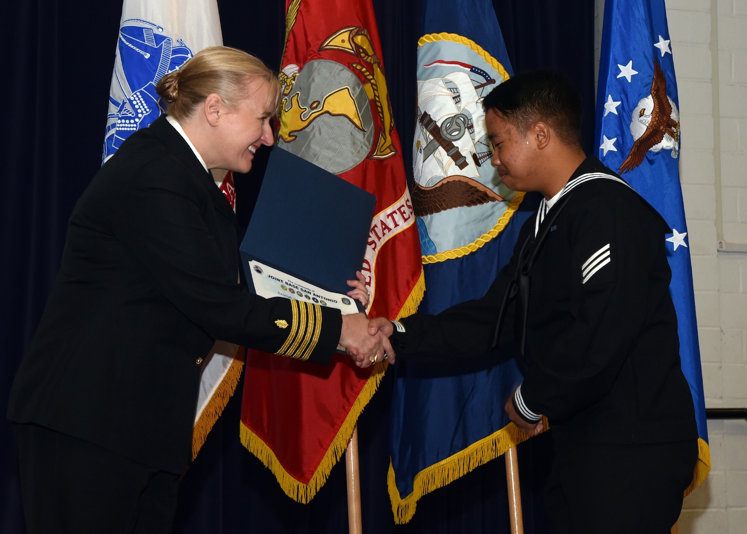 JOINT BASE SAN ANTONIO-FORT SAM HOUSTON – (March 27, 2024) – Capt. Jennifer Buechel, of Woodhaven, Mich., commanding officer, Naval Medical Research Unit (NAMRU) San Antonio, congratulates Navy Seaman Ryan Dhel Elamparo, 20, of the Philippines, on becoming an U.S. citizen during the U.S. Citizenship Naturalization Oath Ceremony held at the Military and Family Readiness Center.  Fifteen service members from the U.S. Army, Navy, and Air Force became U.S. citizens from the countries of China, Kenya, Jamaica, Nigeria, Vietnam, Venezuela, and The Philippines. Buechel, a Navy nurse, delivered the keynote address.  NAMRU San Antonio’s mission is to conduct gap driven combat casualty care, craniofacial, and directed energy research to improve survival, operational readiness, and safety of Department of Defense (DoD) personnel engaged in routine and expeditionary operations.  It is one of the leading research and development laboratories for the U.S. Navy under the DoD and is one of eight subordinate research commands in the global network of laboratories operating under the Naval Medical Research Command in Silver Spring, Md. (U.S. Navy photo by Burrell Parmer, NAMRU San Antonio Public Affairs/Released)