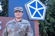 Staff Sgt. Arma Norried, a signal support systems specialist assigned to the 415th Civil Affairs Battalion, poses in front of the V Corps logo in Poznan, Poland, March 19, 2024. Norried supports the communication systems and signal networks between the civil affairs teams deployed to Poland. (U.S. Army photo by Staff Sgt. Jameson Harris)