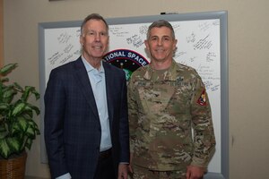 two men stand next to each other smiling for a photo