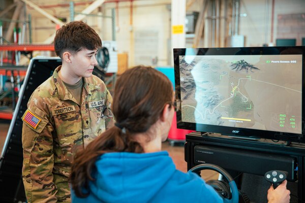 A high school student is shown an Oklahoma National Guard military occupational specialty simulator during the 137th Special Operations Wing 2024 Student Flight Fest Invitational event held at Will Rogers Air National Guard Base, Oklahoma March 28, 2024. The invitational allowed for students, educators and other visitors from across the state to broaden their understanding of what the Oklahoma Air National Guard has to offer through aircraft displays, interactive stations, and discussions with Airmen and Soldiers from diverse career fields.