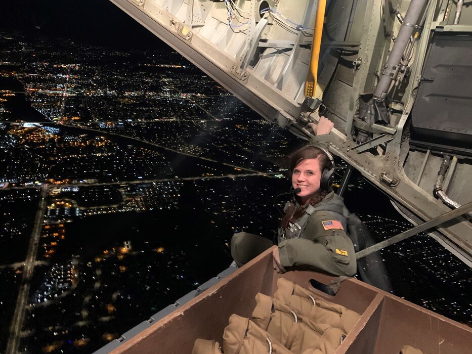 U.S. Air Force Master Sergeant Jessica Abad sits on the back of an opened EC-130H Compass Call while flying over Tucson, Arizona. Abad performed a “Confidence maneuver,” which is where the ramp and door are opened, and a crew member gets to sit on the ramp while flying. (Courtesy Photo)
