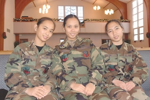 Three sisters in Air Force uniforms sit side-by-side.