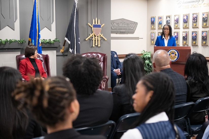 A person standing at a podium speaks to an audience.