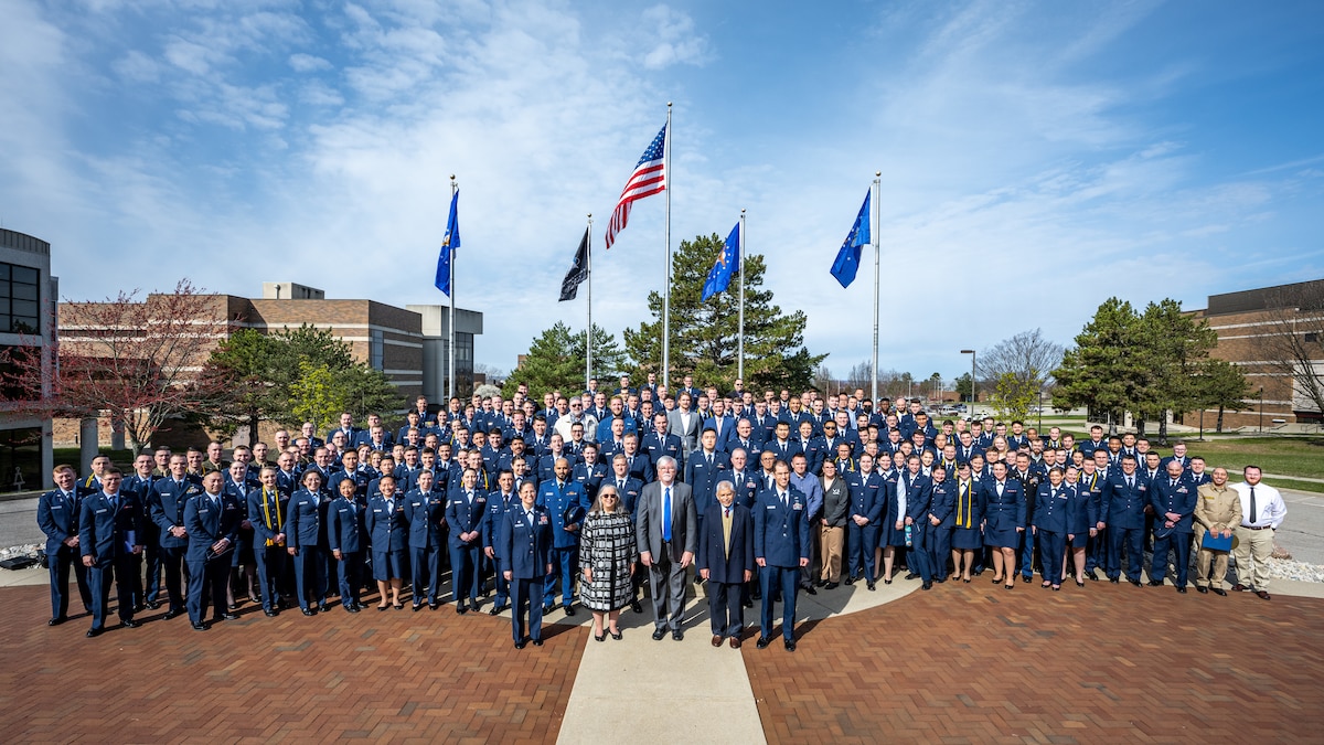 A group photo of AFIT class of 2024 in front of flag pole