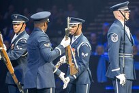 military personnel perform drill movements before a large audience