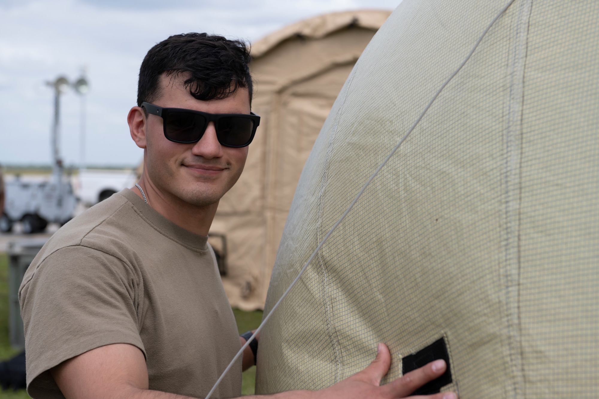 A person leaning against a blown up satellite posing for a photo.