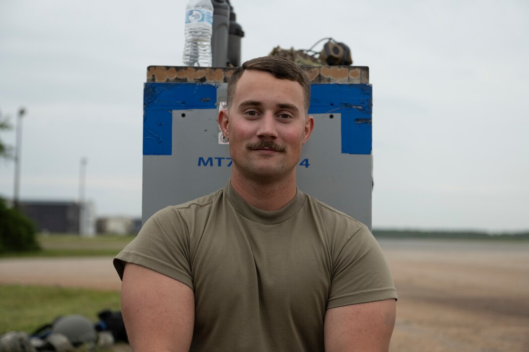 A person sitting on the ground, leaning against a tool box, posing for a photo.