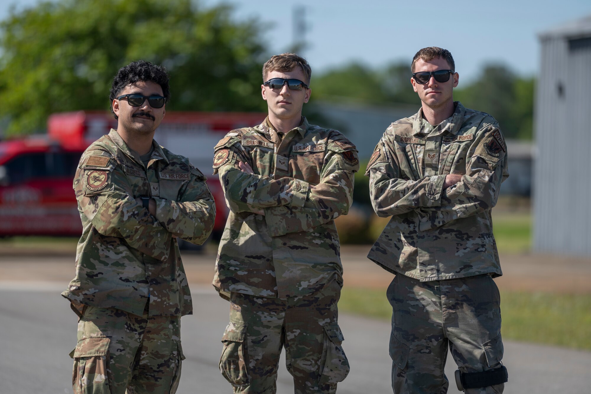 A photo of three people crossing their arms in front of themselves, posing for a photo.