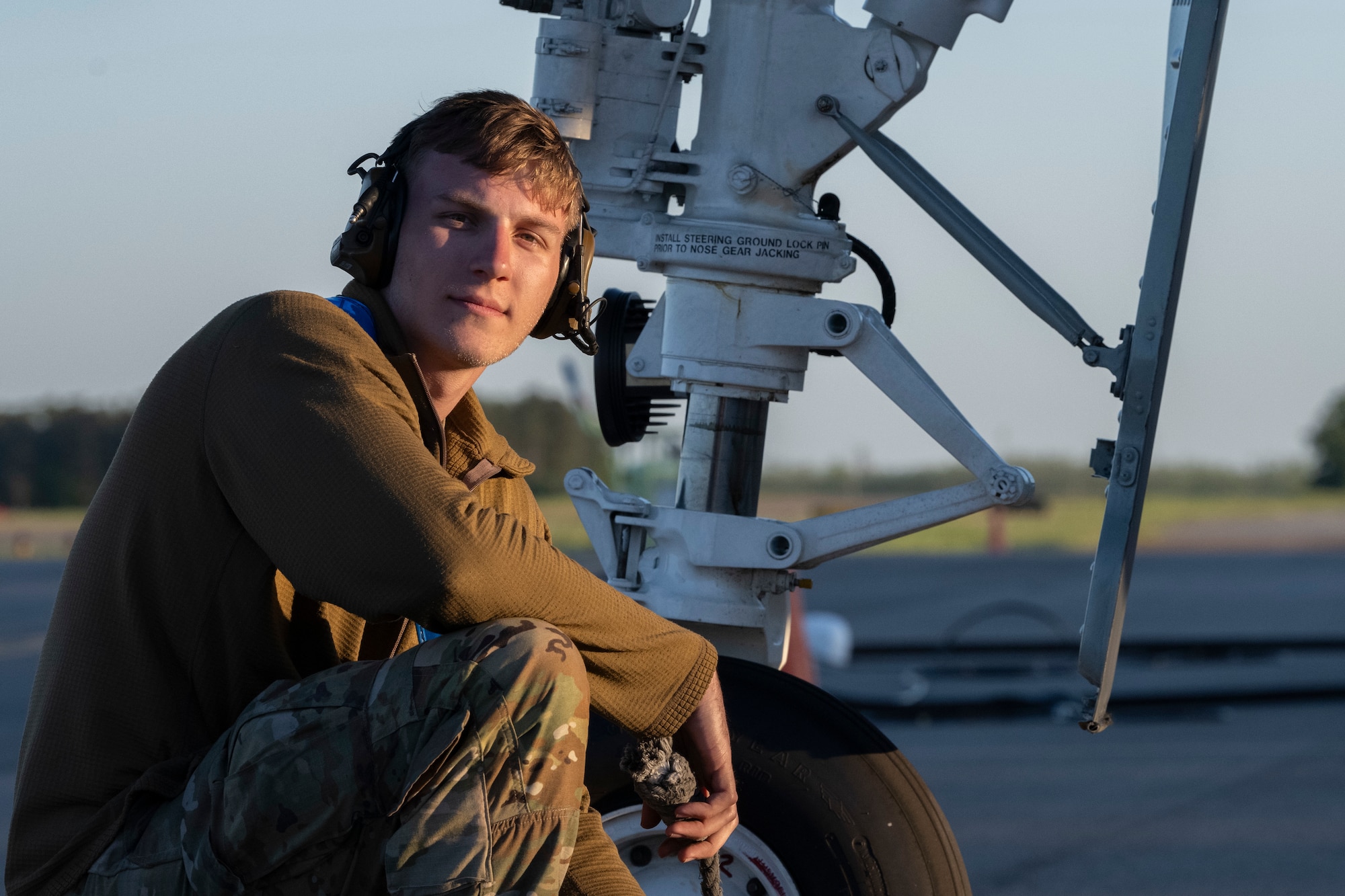 A person squatting down next to an A-10C wheel.