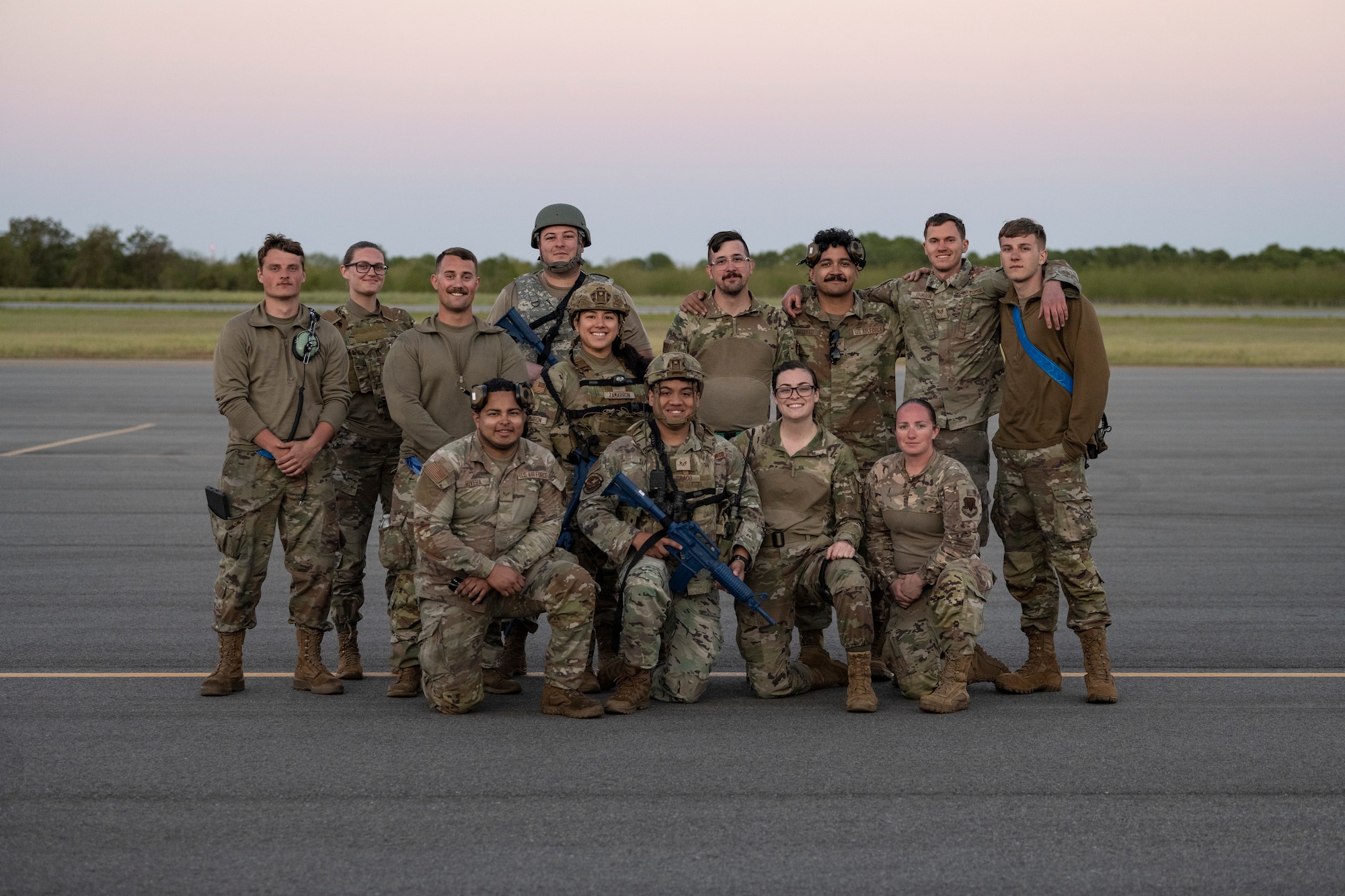 A group of people posing for a photo on a flight line.