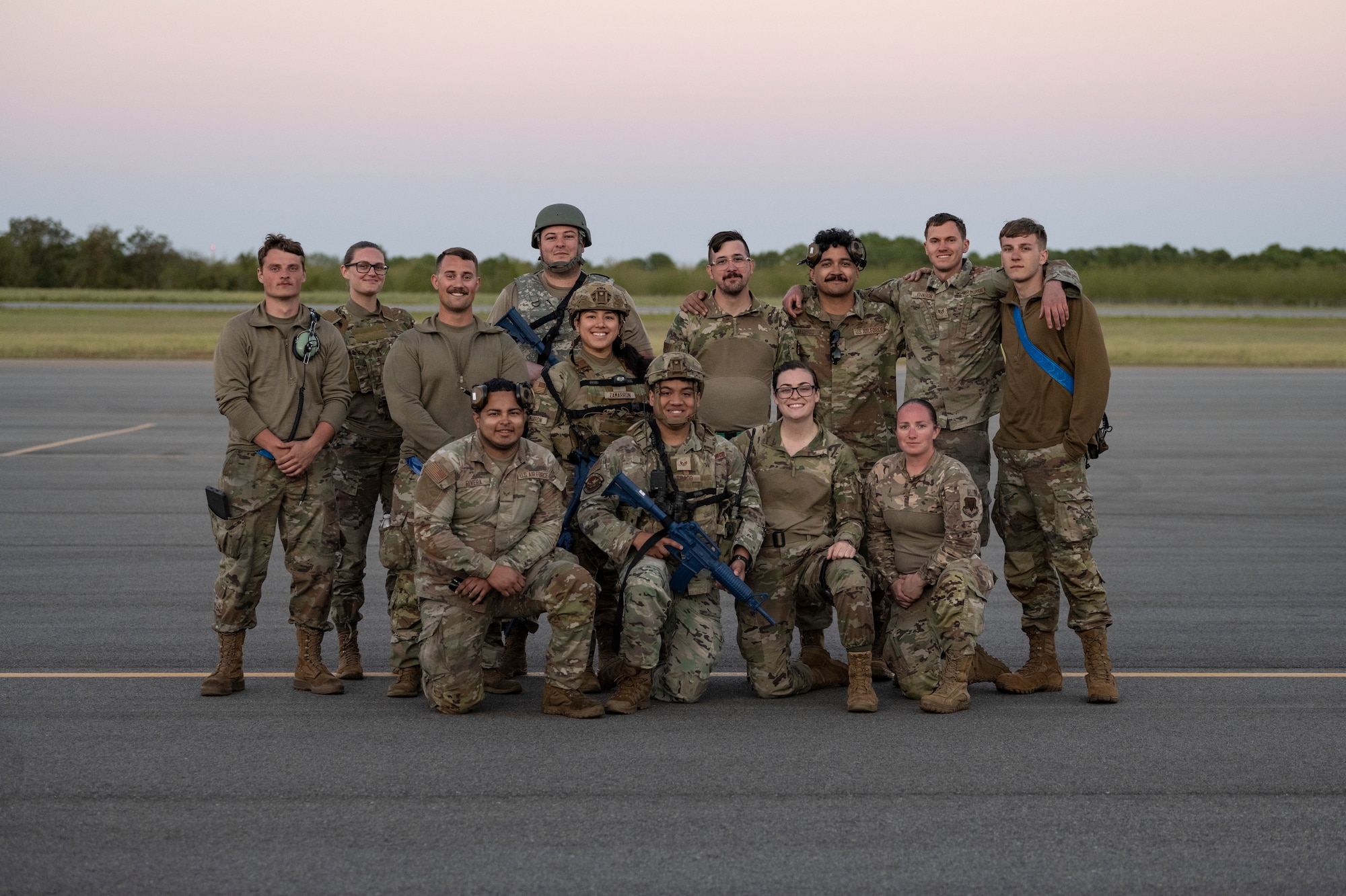 A group of people posing for a photo on a flight line.