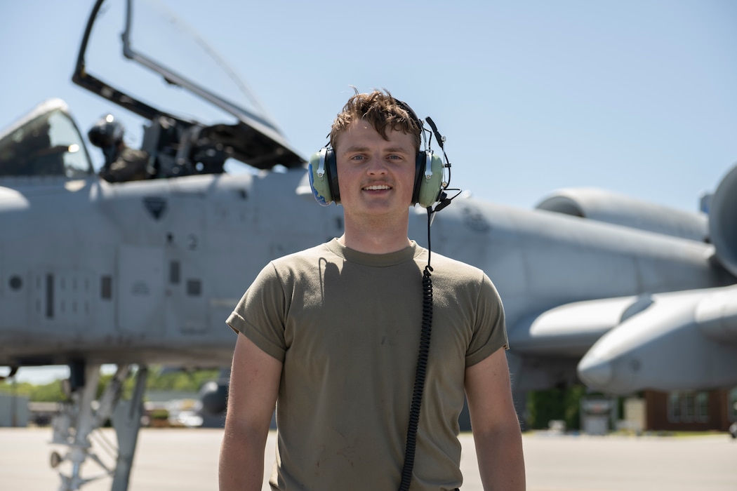 A person posing for a photo with an A-10C in the background.