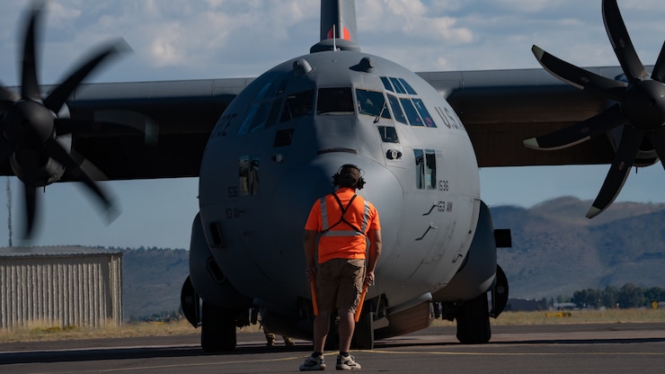 Fixed Wing Parking Tender for the Bureau of Land Management Dan Wilson assists with launching an aerial firefighting aircrew aboard a Modular Airborne Fire Fighting System (MAFFS) equipped C-130H assigned to the 153rd Airlift Wing at Klamath Falls Air Tanker Base, Oregon, Aug. 12, 2023. U.S. Air Force C-130H MAFFS-equipped aircraft, as requested by the National Interagency Fire Center and approved by the Secretary of Defense, provide unique firefighting capabilities to support wildfire suppression efforts against the Wiley, Jerry Ridge, and Ben Harrison Fires. Air Forces Northern, U.S. Northern Command's Air Component Command, is the DoD's operational lead for aerial military support to the National Interagency Fire Center, assisting with wildland fire suppression operations when requested. (U.S. Air Force photo by Master Sgt. Nieko Carzis)
