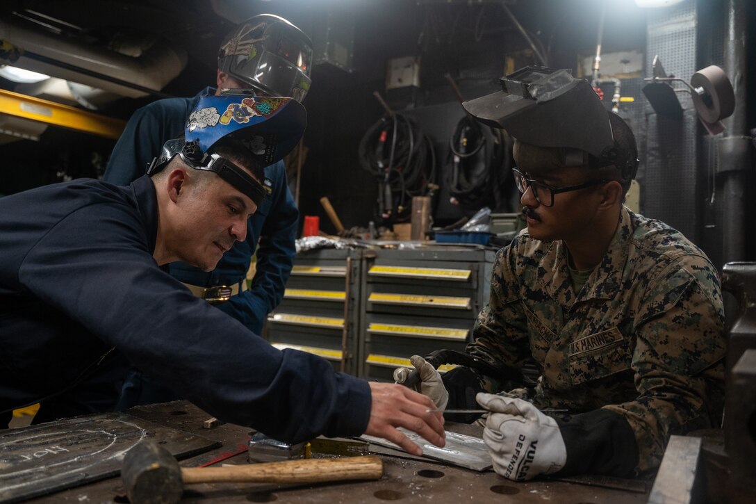 U.S. Navy Chief Petty Officer Erick Belena, a hull technician with the amphibious assault ship USS Wasp (LHD 1), instructs U.S. Marine Corps Sgt. Lucas Camacho, a ground radio electronics repairman with the 24th Marine Expeditionary Unit (MEU), on how to weld and metal work on April 12, 2024. The USS Wasp, with embarked 24th MEU, is underway in the Atlantic Ocean completing integrated naval training as a WSP ARG-24th MEU team. (U.S. Marine Corps photo by Cpl. Elton Taylor)