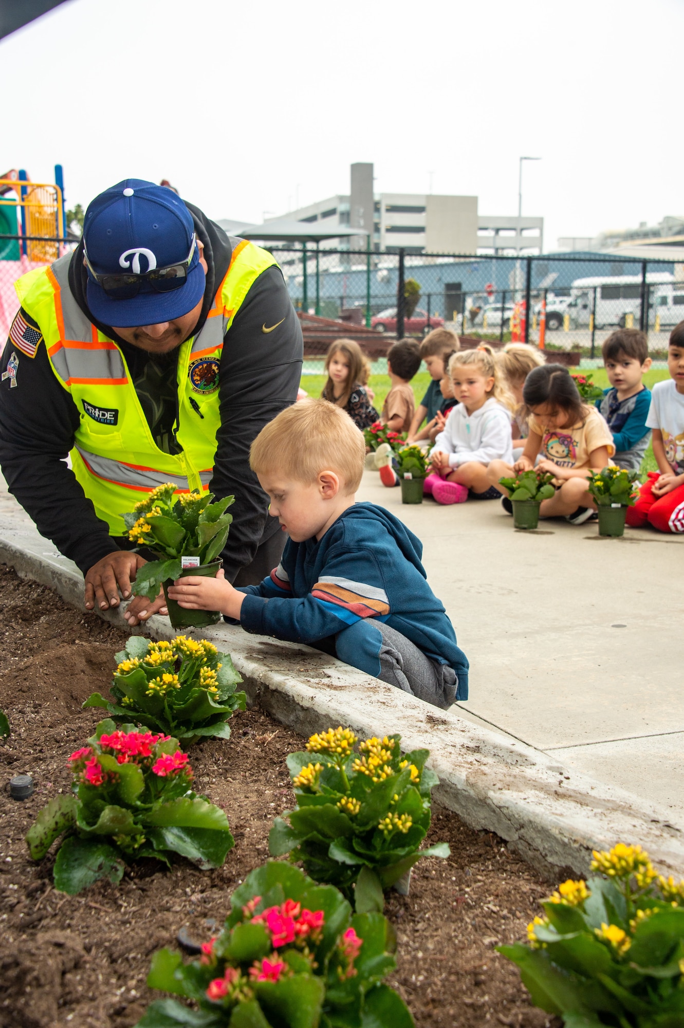 A Civil Engineer Squadron member helps a little boy plant a flower in front of the Child Development Center.