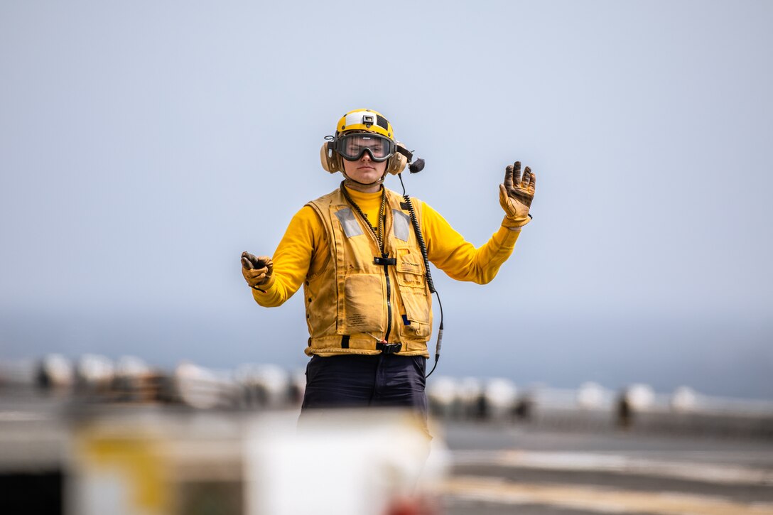 A U.S. Navy Sailor with the USS Wasp (LHD 1) gestures commands during flight operations aboard the USS Wasp while the Wasp (WSP) Amphibious Ready Group (ARG) conducts a simulated strait transit during Composite Training Unit Exercise (COMPTUEX) in the Atlantic Ocean, April 26, 2024. The WSP ARG-24th MEU is conducting COMPTUEX, their final at-sea certification exercise under the evaluation of Carrier Strike Group 4 and Expeditionary Operations Training Group. Throughout COMPTUEX, the WSP ARG-24th MEU is evaluated across a spectrum of scenarios that determine their readiness to deploy. (U.S. Marine Corps photo by Gunnery Sgt. Hector de Jesus)