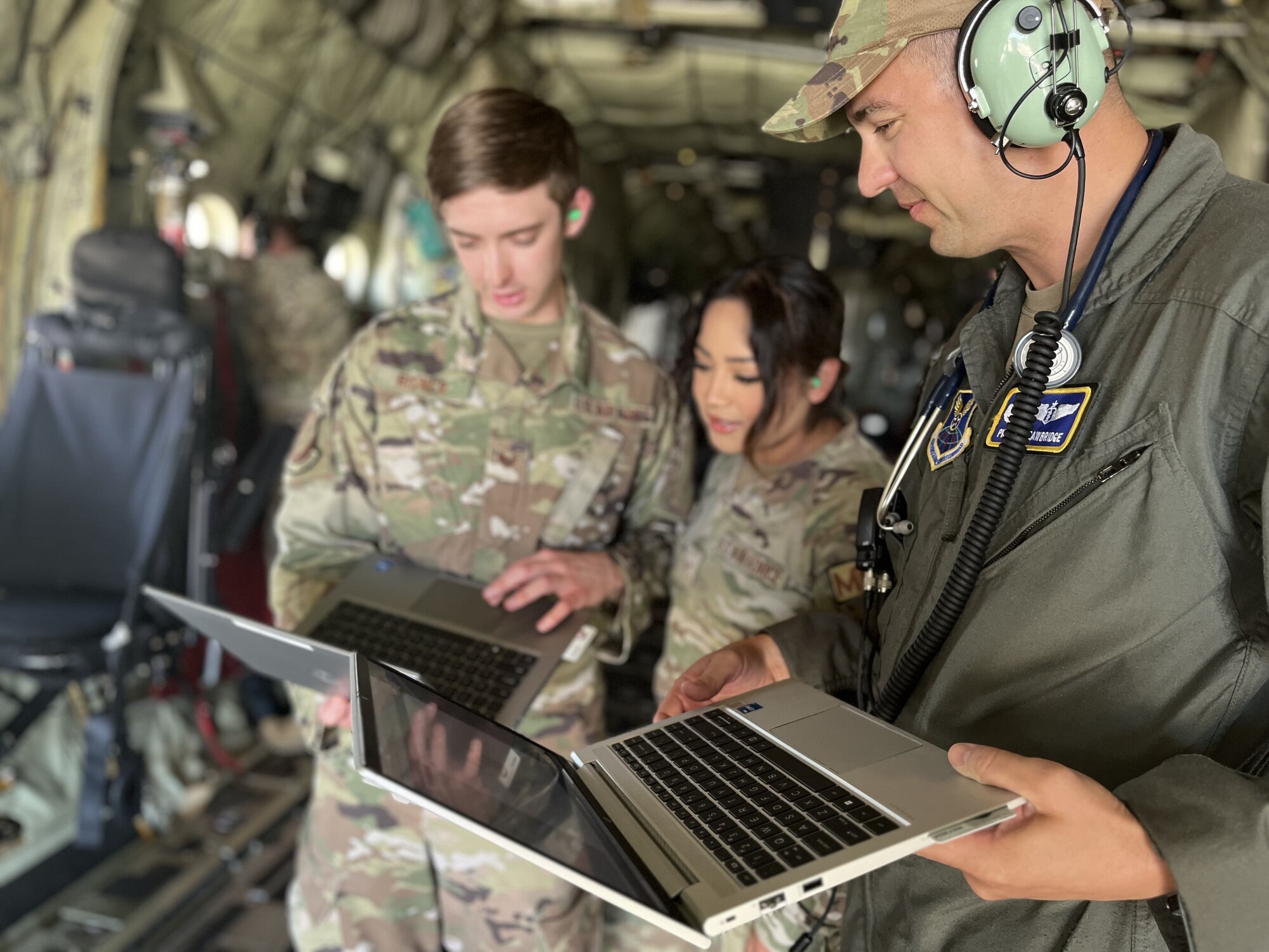 Three medics stand with laptops testing the connectivity of a Starlink satellite.