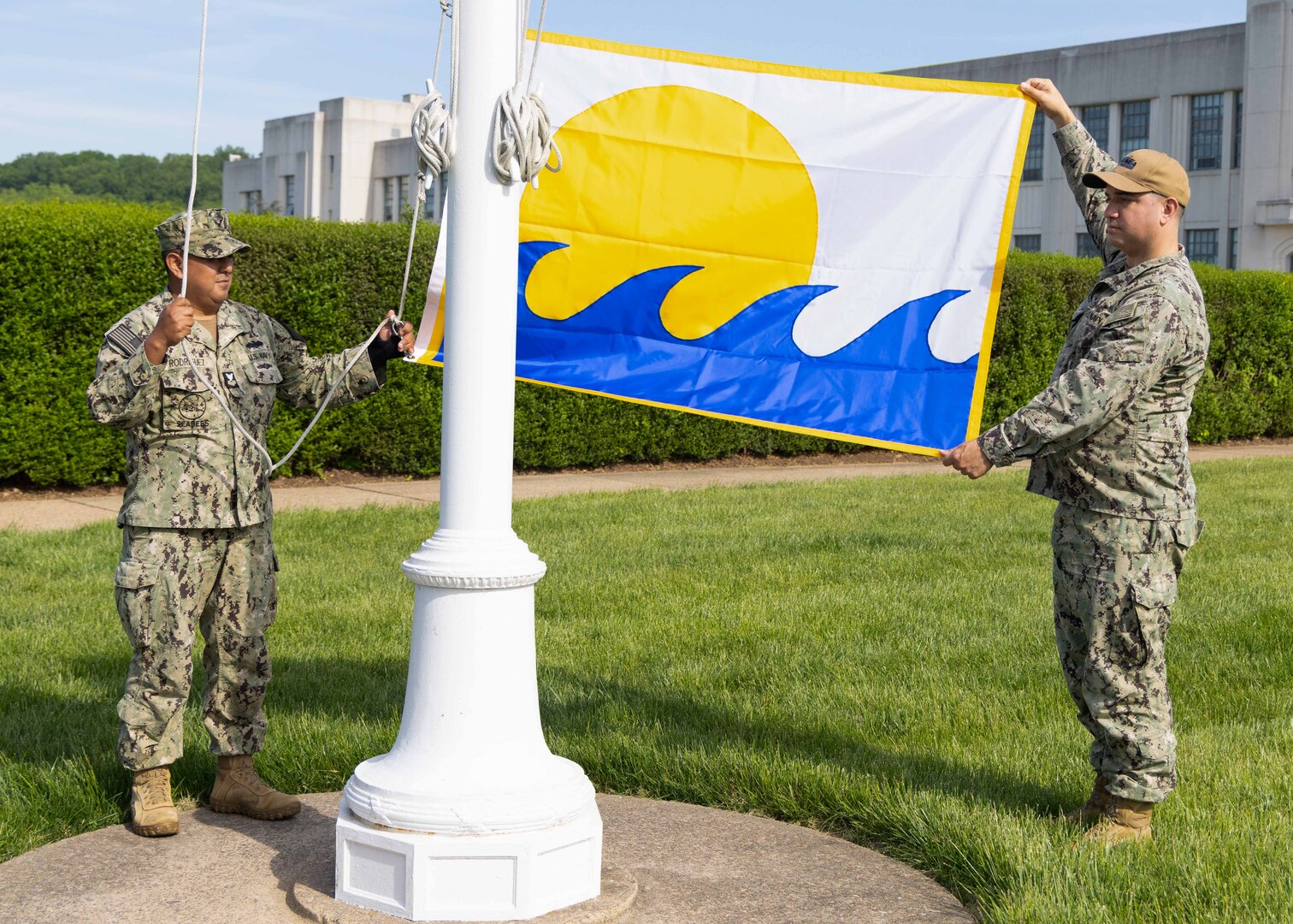 Navy reservists lift the SECNAV Energy Excellence Flag in front of Building 2 at Naval Surface Warfare Center, Carderock Division in West Bethesda, Md., on April 30, 2024.