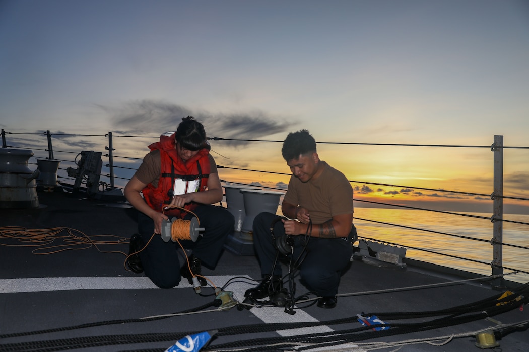 Quartermaster Seaman Alyssa Gutierrez, left, and Culinary Specialist 2nd Class Erick Norman, right, set up a sound powered phone on the fo’c’sle aboard the Arleigh Burke-class guided-missile destroyer USS Howard (DDG 83)