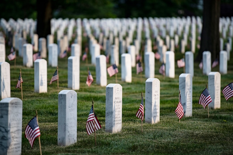 Lines of gravestones with small American flags.