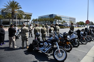 An line of motorcycles is depicted making a perfect back drop during the opening remarks for Motorcycle Safety Awareness Day in the Commissary Parking lot.