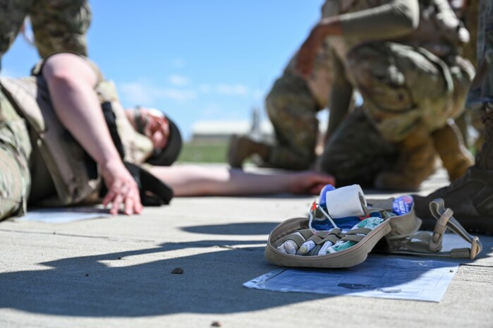 A medical pack with an Airman laying on the ground in the background