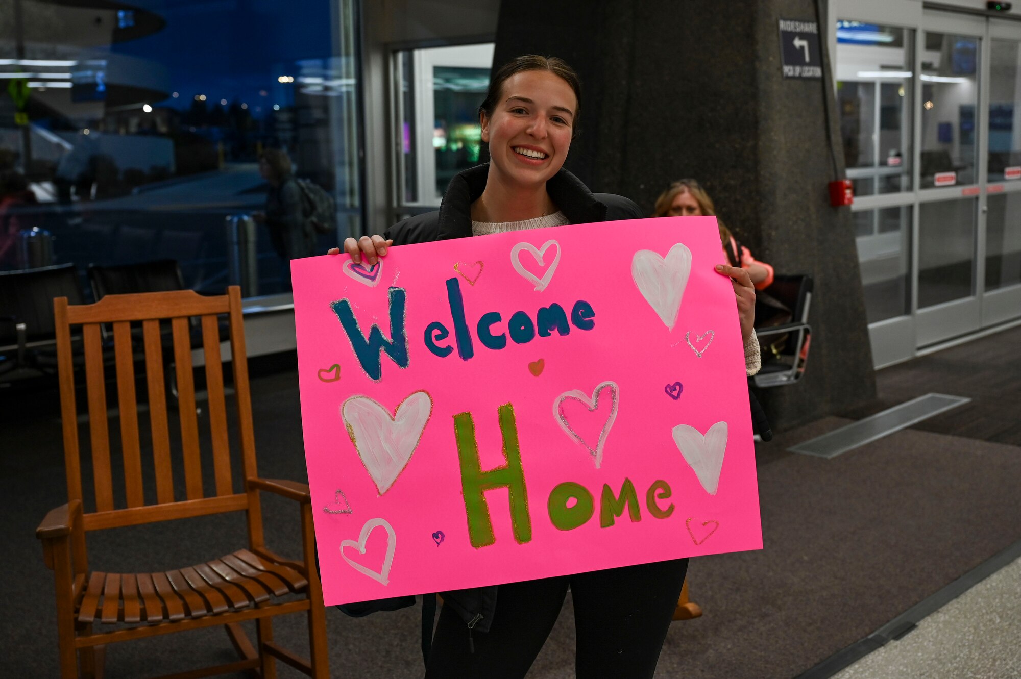 A woman holds a welcome home sign.