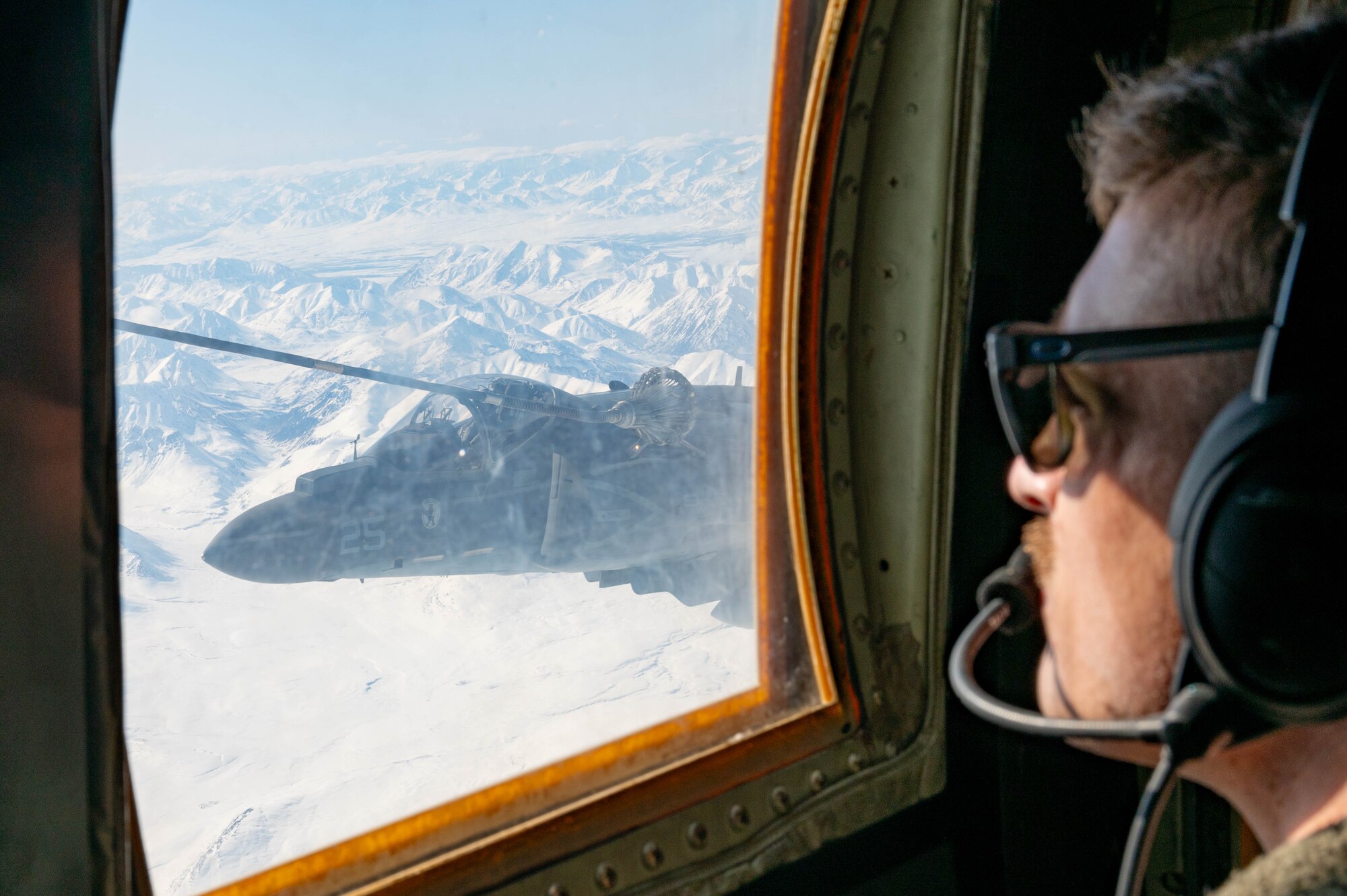 U.S. Marine Staff Sgt. Chase Anderson, a flight engineer assigned to the Marine Aerial Refueler Transport Squadron (VMGR) 234 watches over a V-8B Harrier II assigned to the Marine Attack Squadron (VMA) 223 as it refuels during Red Flag-Alaska 24-1 in the Joint Pacific Alaska Range Complex, Alaska, April 25, 2024.