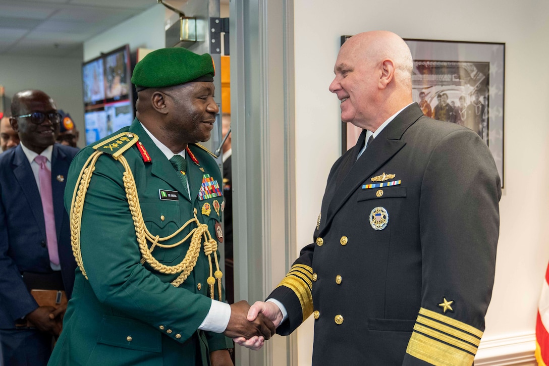 Navy Adm. Christopher W. Grady, vice chairman of the Joint Chiefs of Staff, shakes hands with a uniformed Nigerian leader indoors.
