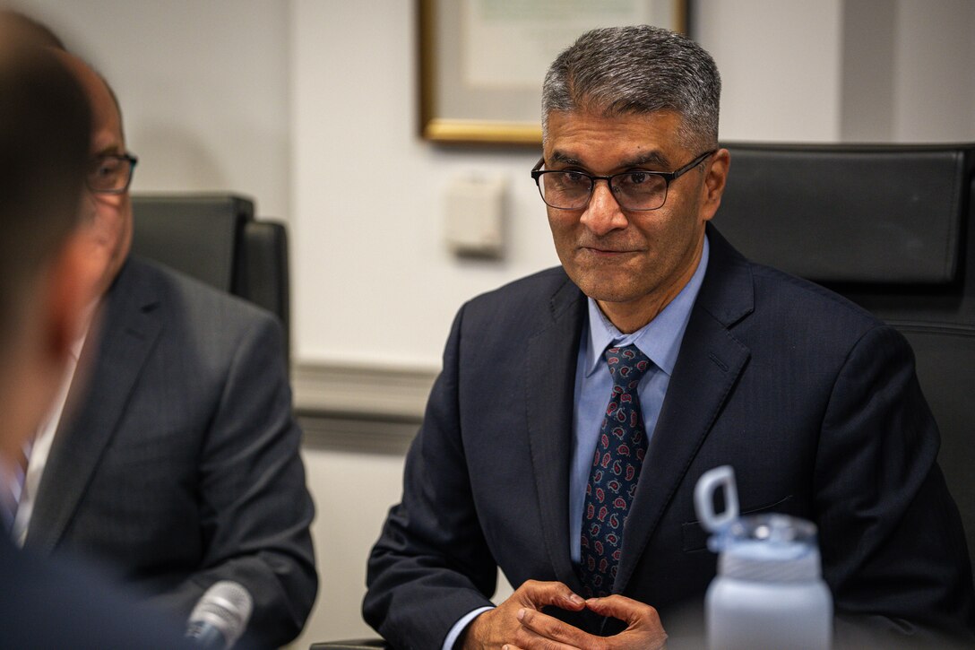 A panelist listens while seated in a chair.