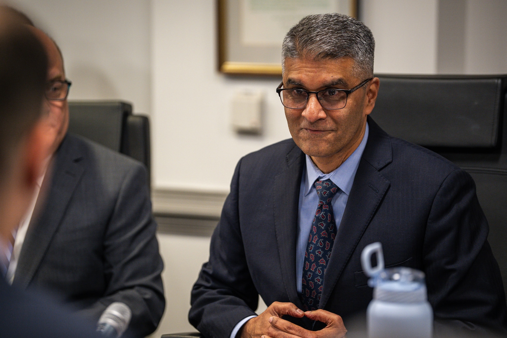 A panelist listens while seated in a chair.