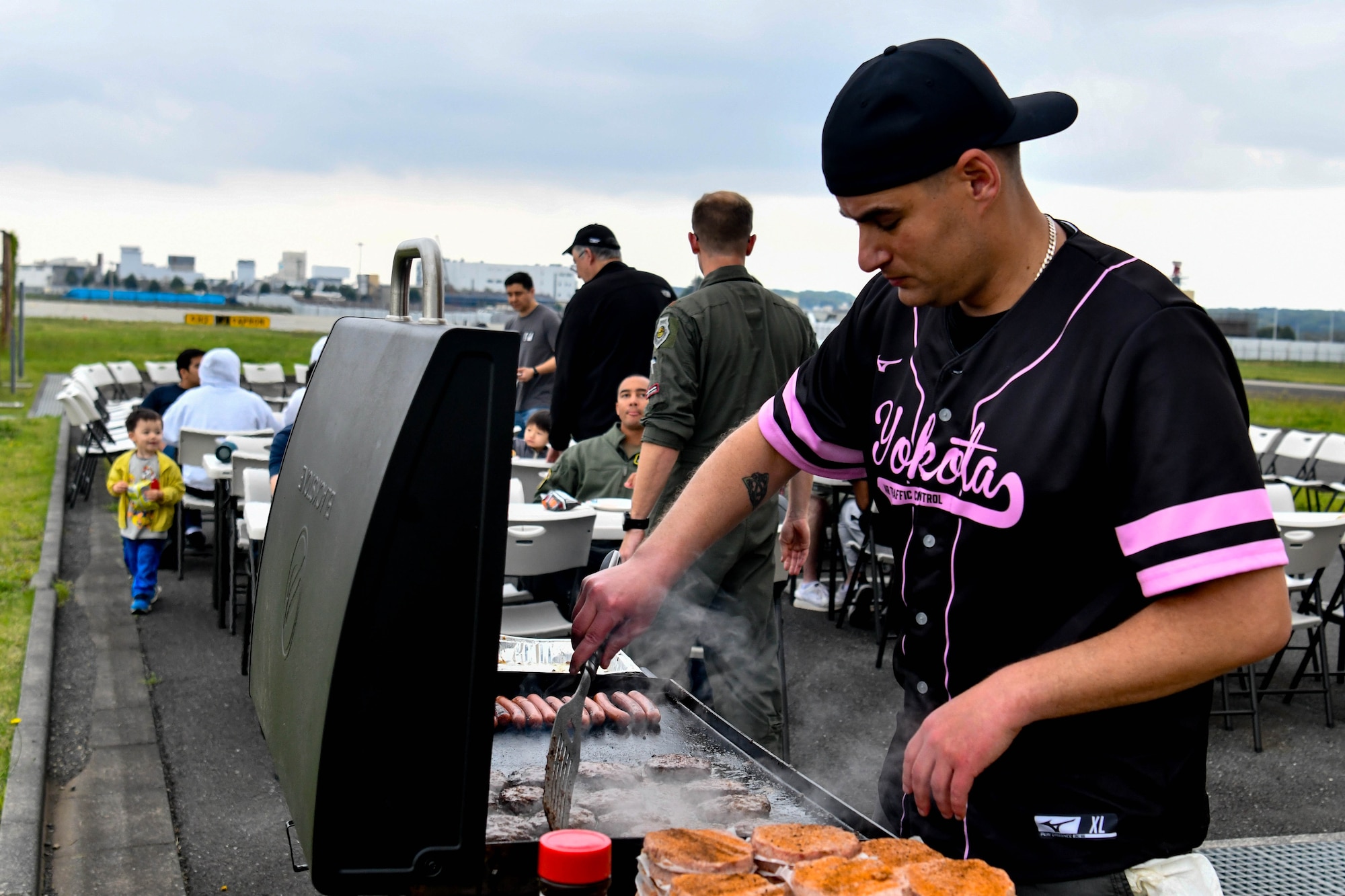 U.S. Air Force Master Sgt. Jonathon Parker, 374th Operations Support Squadron tower chief controller, cooks food on a grill.