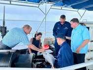 Capt. Nicholas Simmons, commander of U.S. Coast Guard Forces Micronesia/Sector Guam, and Chief Petty Officer Carleton Kleinschrodt discuss fish with Congressman Sam Graves, Chairman of the House Committee on Transportation and Infrastructure, and Congressman Mike Bost, Chairman of the House Committee on Veterans Affairs aboard USCGC Oliver Henry (WPC 1140) in Guam on April 26, 2024. The congress members led a delegation, which included Congressmen David Rouzer, Troy Nehls, and Mark DeSaulnier, along with Guam Delegate James Moylan and key staff from both committees, spent the afternoon with crews, gaining firsthand insights into the critical operations of the Fast Response Cutters (FRCs) in the region. The delegation also toured essential infrastructure sites, including the damaged glass breakwater and the Port Authority of Guam, from the cutter and the cutter small boat. These sites are essential for military readiness, impact shipping routes, and influence the economic activity and cost of goods in the Marianas. (U.S. Coast Guard photo by Chief Warrant Officer Sara Muir)